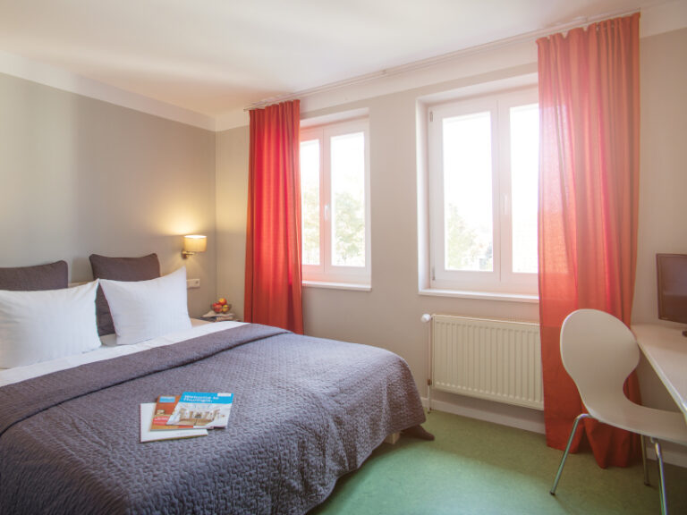 Doppelbett, Fenster und Schreibtisch im AMATO Doppelzimmer